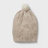 Beige knit beanie with a pom-pom on a light gray background