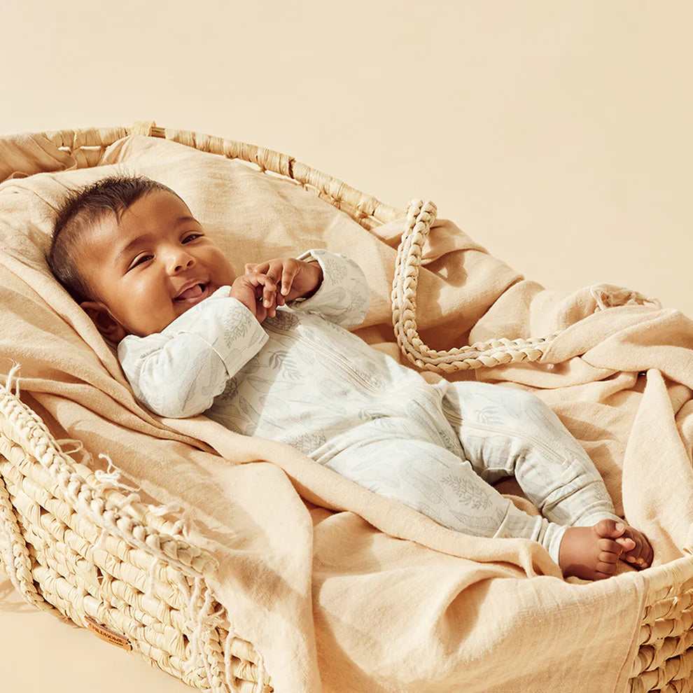 Baby lying in a woven basket with beige blanket
