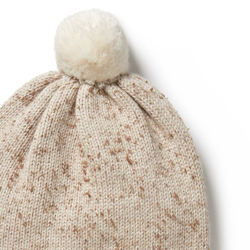 Knitted beanie with a white pom-pom on a light background