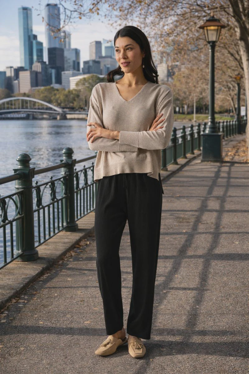 Woman standing on a path by a river with a city skyline in the background