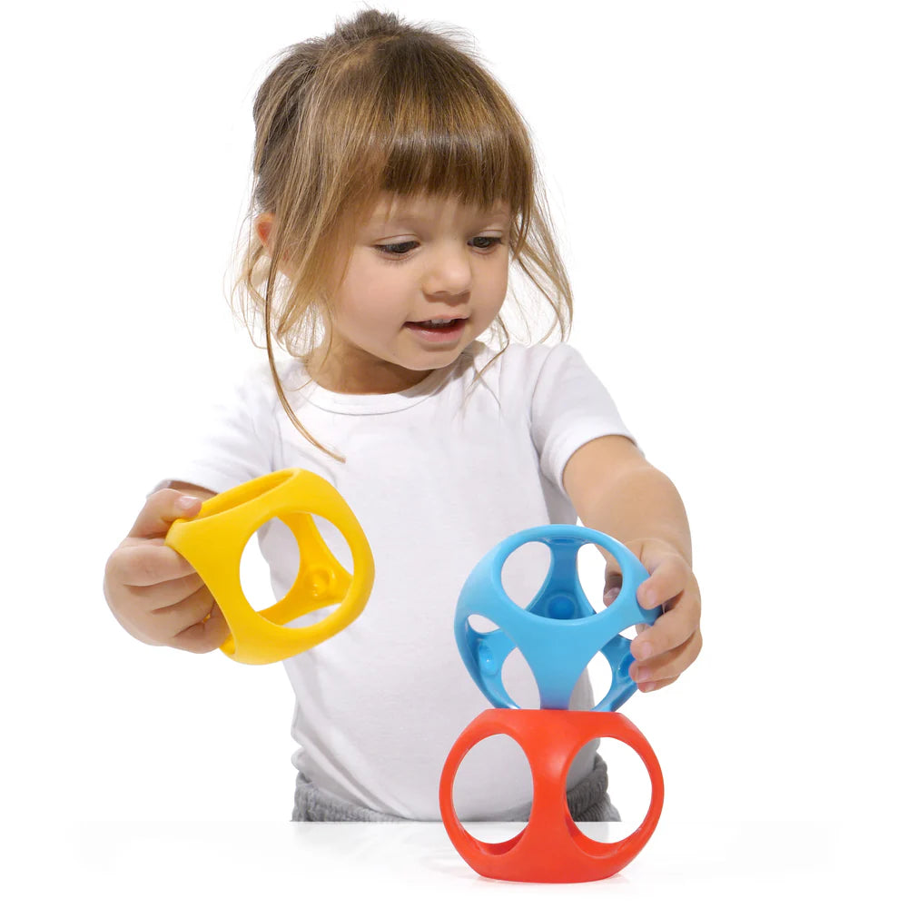 Child holding three colorful plastic toys against a white background