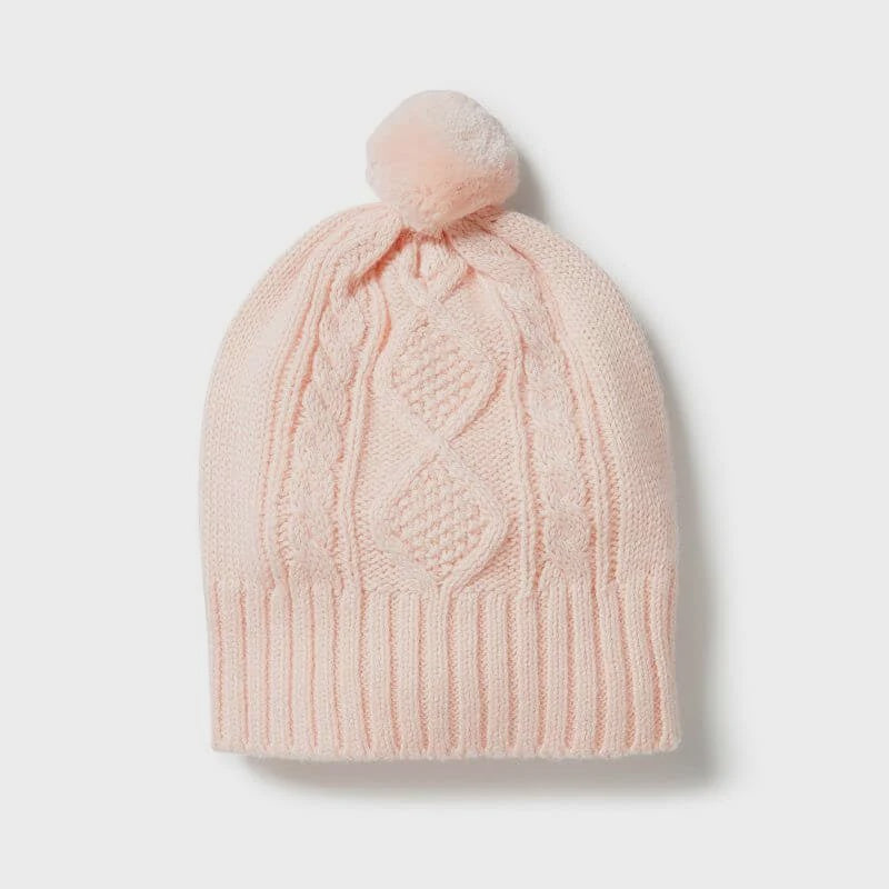 Pink knitted beanie with a pom-pom on a light gray background