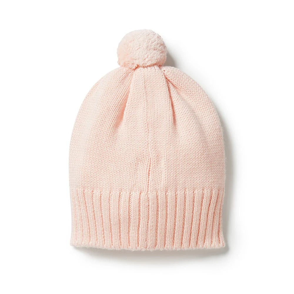 Pink knit beanie with a pom-pom on a white background